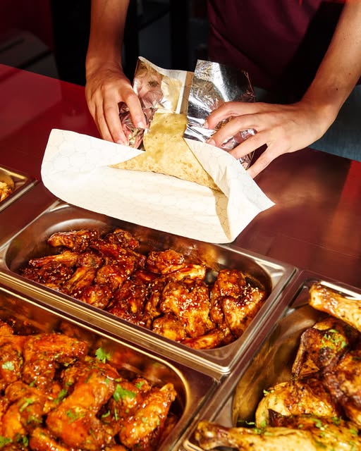 Un burrito qu'on emballe au-dessus des bacs de wings